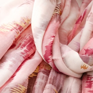 Macro detail of silk scarf featuring gold foil accents and soft abstract watercolor texture