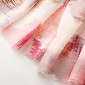 Macro detail of scarf showing gold foil abstract patterns on pink gradient fabric
