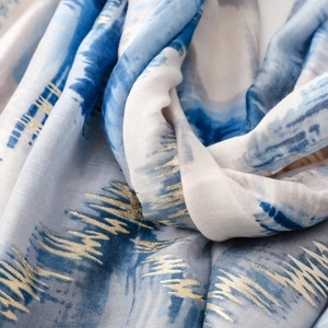 Detail of artistic gold foil waves on lightweight blue silk scarf with ink gradient