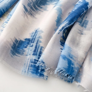 Detail of blue and white printed scarf with gold foil lines and soft frayed edges