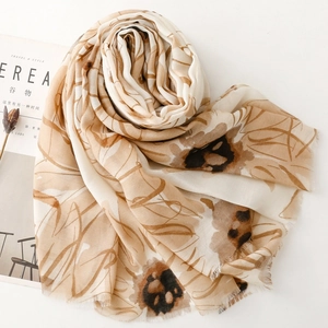 Detailed texture of beige floral scarf with abstract daisy patterns and frayed edges