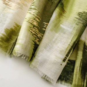Detail of green gradient silk scarf featuring fine gold lines and delicate fringe edges