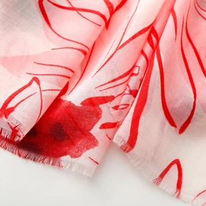 Detail of red floral print on lightweight white scarf fabric with delicate frayed edges