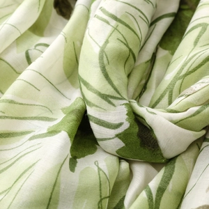 Macro shot of lightweight satin scarf with detailed green leaf floral print and fiber texture
