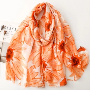 Detail of vibrant orange floral print scarf with soft frayed edges on aesthetic magazine
