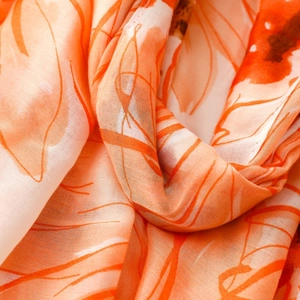Close-up of lightweight orange floral satin scarf showing detailed texture and soft fabric