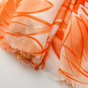 Close-up of lightweight orange daisy scarf featuring woven texture and fringe detail