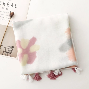 Close-up of cream scarf with floral watercolor prints and bicolor fringe tassels