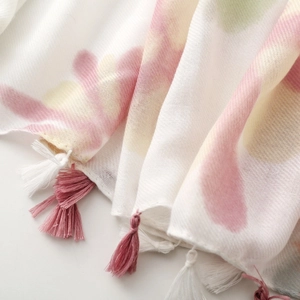 Detail of soft watercolor pattern on scarf fabric with elegant pink and white tassels