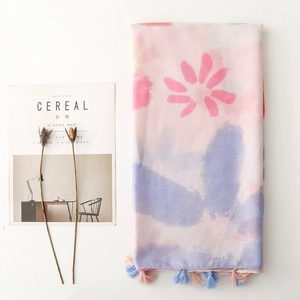 Close-up of soft pastel floral scarf with fine fringe edges and cotton-linen texture