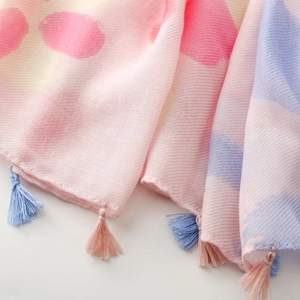 Detailed macro view of soft pink cotton-linen scarf with colorful polka dots and fringe