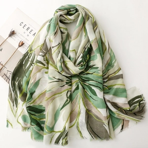 Detailed texture of botanical leaf print on soft satin scarf with gold foil accents