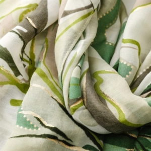 Detail of satin floral scarf showing gold foil leaf patterns and soft green fabric texture