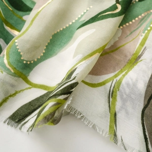 Detail of silk scarf showing forest green abstract print with elegant gold foil accents