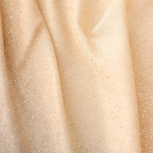 Gros plan sur un tissu pailleté champagne doré avec de fines paillettes et drapé doux