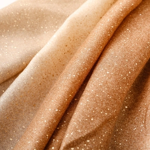 Détail de l'écharpe en coton et lin dégradé chaud avec texture douce et dorure géométrique