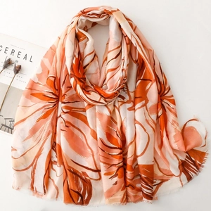 Detail of thin satin scarf with orange floral prints and delicate fringe edge texture