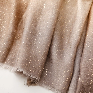 Détail d'une écharpe en coton et lin marron dégradé avec impression dorée et bords frangés