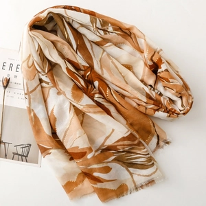 Macro detail of satin scarf with gold foil floral print and frayed fringe edges