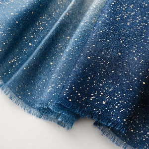 Détail d'un châle bleu dégradé avec imprimé doré scintillant et bords à franges fins