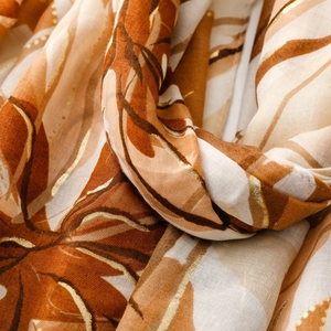 Close-up of lightweight satin scarf featuring gold floral foil print and orchid patterns
