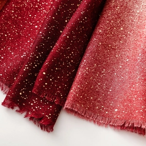 Détail macro de l'écharpe dégradée rouge avec points dorés et franges délicates
