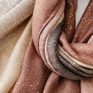 Détail d'une écharpe en dégradé avec paillettes dorées, de beige à bordeaux et gris foncé