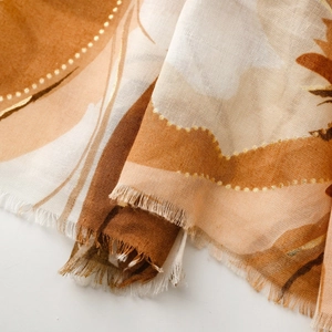 Macro view of floral print scarf with gold accents and fine fringe edge detail