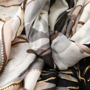 Detailed macro view of thin satin scarf with floral patterns and gold foil stamping