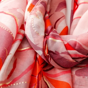 Detailed macro shot of floral print scarf with elegant gold foil accents and woven texture