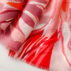 Detailed macro view of thin satin scarf with gold stamping and white orchid floral patterns