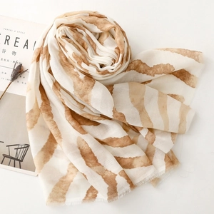 Detail of soft zebra pattern scarf with amber stripes next to a minimalist magazine