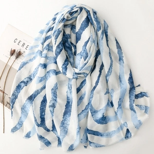 Lightweight blue gradient striped scarf with frayed edges in a minimalist flat lay