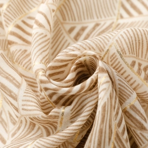 Close-up of lightweight off-white scarf with gold foil accents and leaf print
