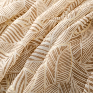 Macro shot of gold-leaf satin scarf fabric with abstract leaf texture and metallic edges