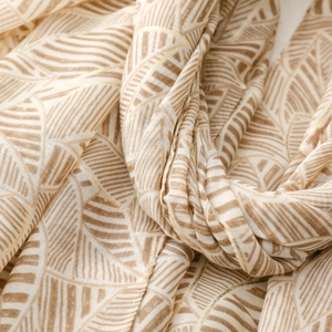 Macro detail of scarf fabric showing golden leaf patterns and soft satin texture