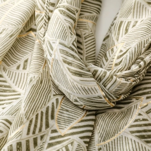 Macro detail of satin scarf showing green leaf patterns with elegant gold foil accents
