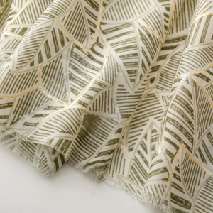 Macro view of green leaf patterns and gold foil texture on a soft satin scarf