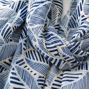 Detailed view of scarf with blue leaf pattern and intricate gold thread embroidery
