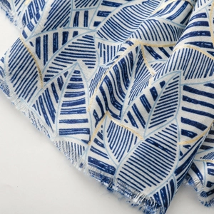 Detailed macro view of the leaf print silk scarf texture with gold foil and frayed edges