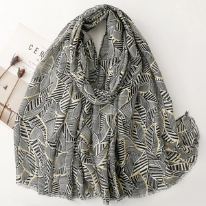 Black and white leaf pattern scarf with gold accents and frayed edges on white background