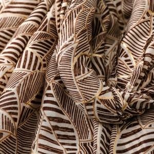 Close-up of lightweight satin scarf featuring gold foil leaf patterns and texture