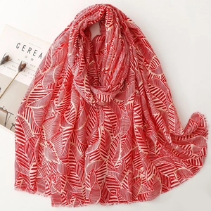 Macro detail of red and white leaf print satin scarf with raw fringe edges and soft texture