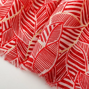 Close-up of red and white leaf pattern scarf with metallic gold thread and frayed edges