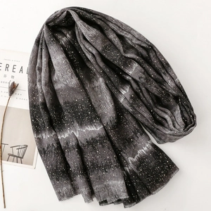 Detail of grey gradient scarf with golden star pattern and soft frayed edges