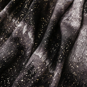 Macro detail of black cotton linen scarf with gold foil accents and soft fabric texture