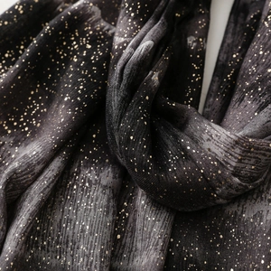 Macro detail of soft black and grey fabric with golden gradient glitter and fringed edges