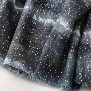 Macro detail of dark blue gradient scarf fabric with gold glitter starry pattern