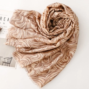 Gros plan d'une écharpe en coton-lin à motif marbre latte doré et bords frangés