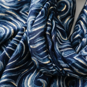 Détail d'une écharpe en soie bleu marine avec motif doré ondulé style Nuit Étoilée